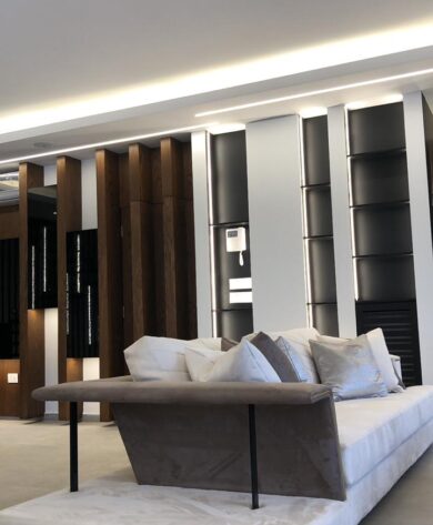 White couch with a sideboard and a wall behind it with wooden veneer adding to the elegant living room