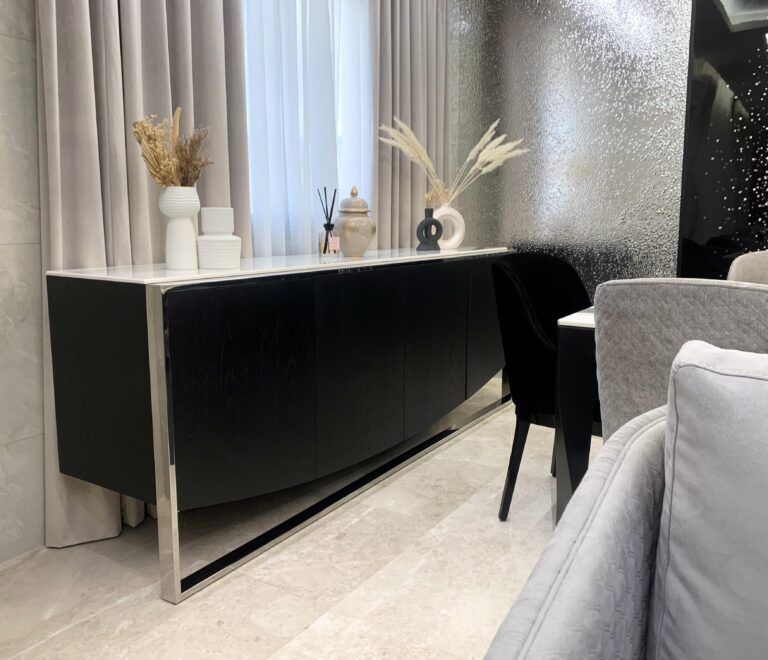 A picture showcasing the sideboard with its black wood panels, curvy design, stainless steel frame and white ceramic top