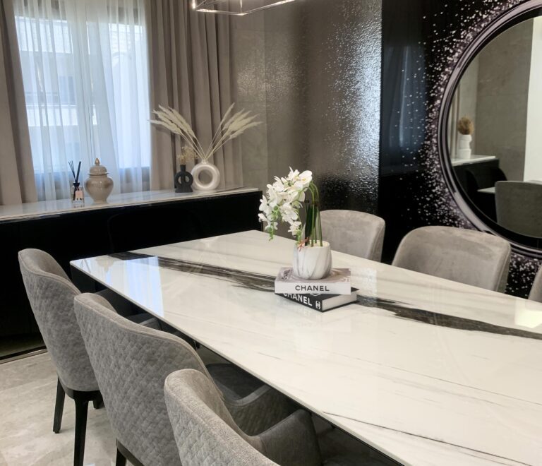 A side view of the luxurious dining table with its black pattern and the sideboard in the background