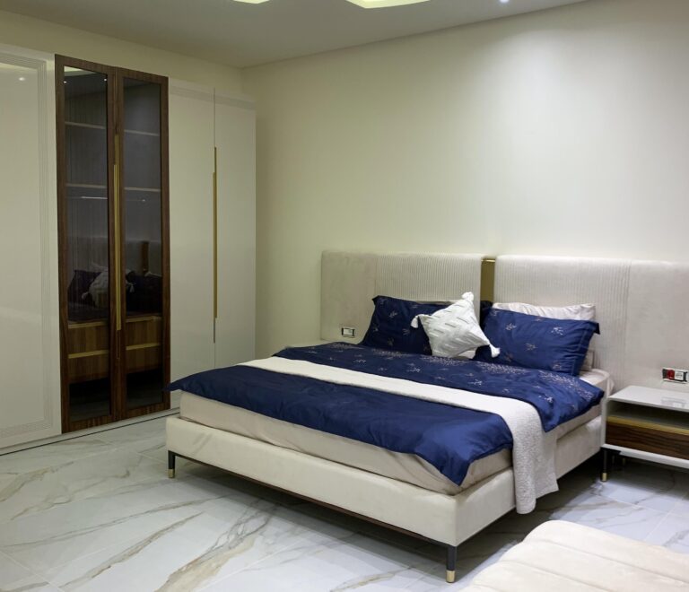 Gest bedroom showing a luxury bed and wooden crafted closet with a glass center panel