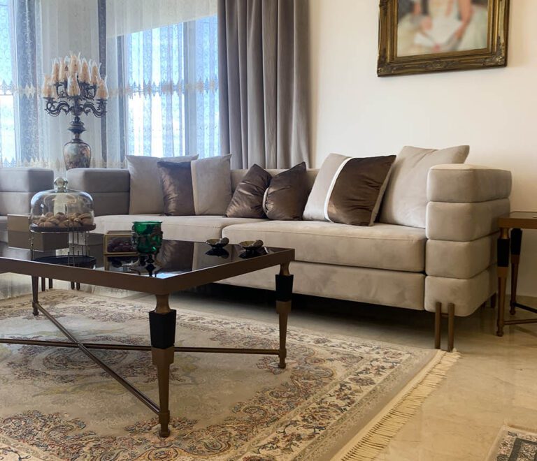 An elegant beige sofa with a background of beautiful drapes and a victorian style frame on the side